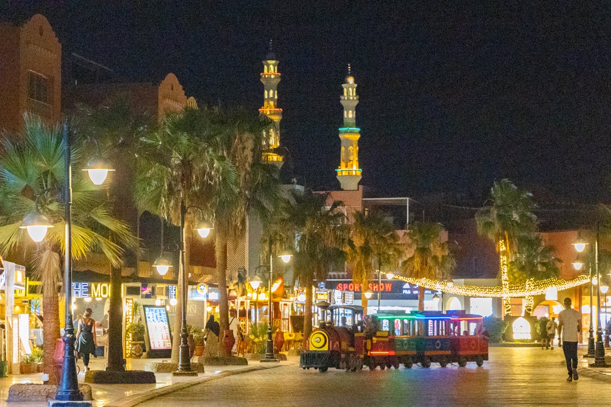Night-time marina promenade with a small tourist train